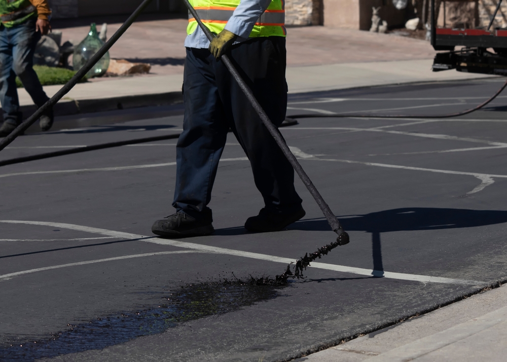 Worker,Spraying,Slurry,Tar,On,Street,During,Resurfacing,Project