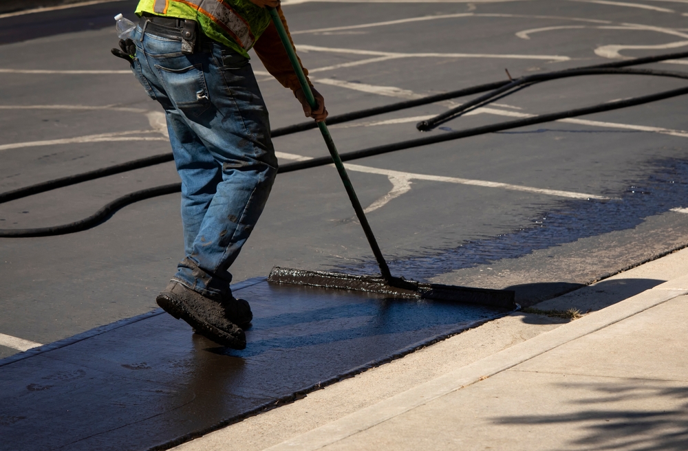 Worker,Using,A,Sealcoating,Brush,During,Asphalt,Resurfacing,Project