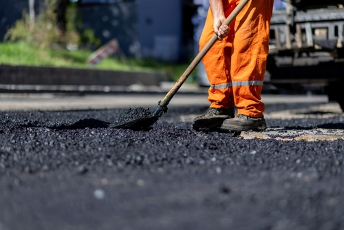 A,Construction,Worker,In,Bright,Orange,Attire,Is,Evenly,Distributing